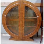 An Art Deco walnut circular display cabinet enclosed by 2 doors, on flared base