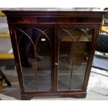 A mahogany reproduction display cabinet enclosed by 2 arched glazed doors