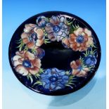 A Moorcroft plate decorated with peonies on a blue ground