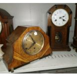 An early 20th century oak case mantel clock with ebonised pillars, white enamel dial and striking