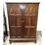 An early 20th century Jacobean style part fitted oak gent's wardrobe, the twin door each with 6