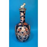 A 19th century Japanese Imari bottle vase with fluted lower section and cover surmounted by a dog of