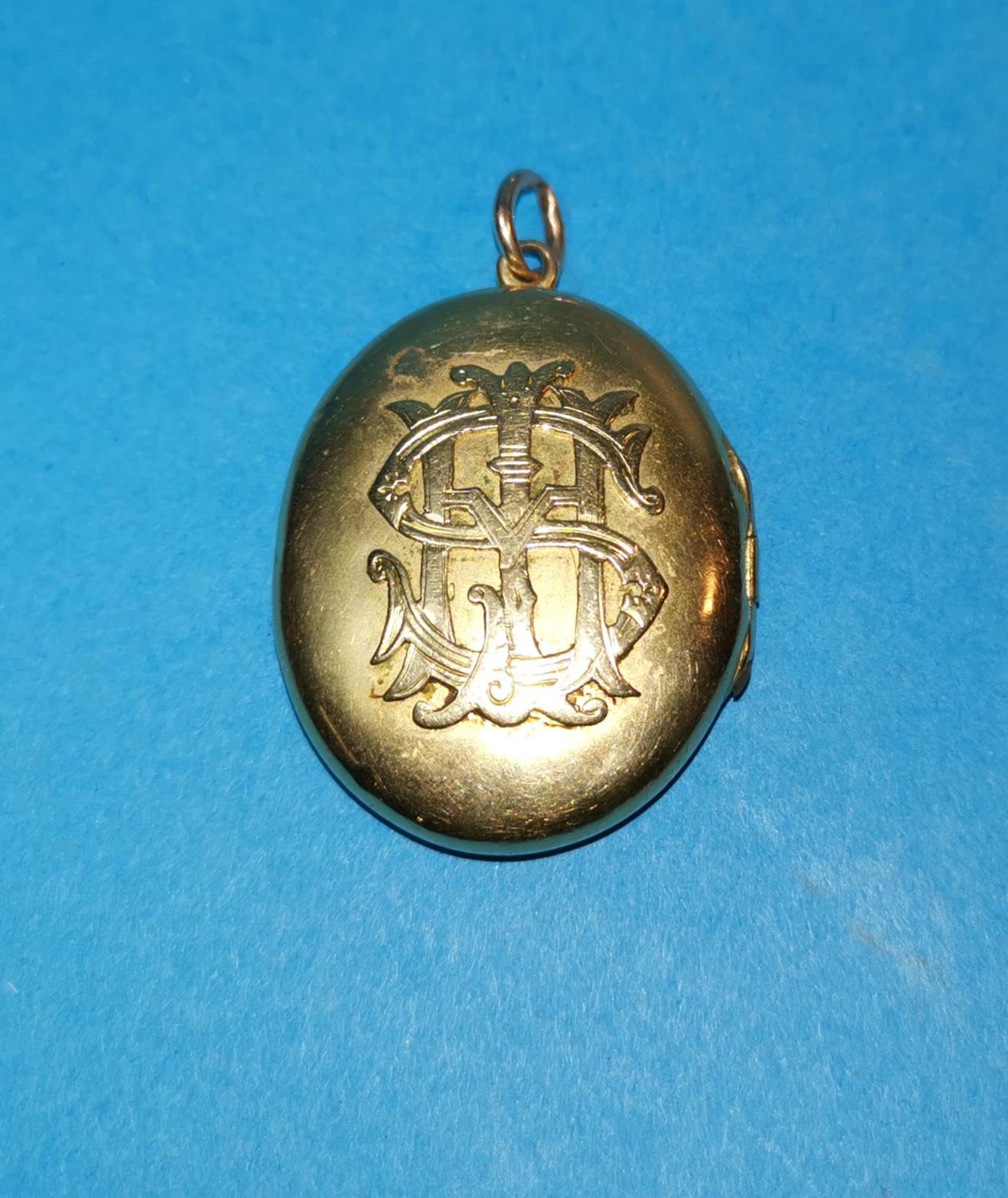 A yellow metal monogrammed locket, unmarked, tests as 14c, gross weight 19.5gm