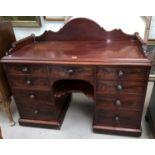 A mid-Victorian figured mahogany knee hole desk / wash stand with low shaped raised back and