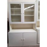 A white laminate wall unit with 2 glazed upper cupboards and cupboard below