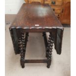 A 1930's scalloped and canted oak drop leaf gate dining table on barley twist supports