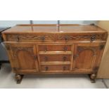 An oak Jacobean style sideboard with carved decoration to doors and drawers, 2 cupboards and 5