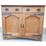 An oak Arts and Crafts side cabinet with double drawers and cupboards with copper fittings