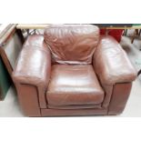 A large club style armchair and pouffe in brown leather