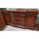 A reproduction dwarf side cabinet in yew wood, with 4 central drawers, and cupboard and drawers to