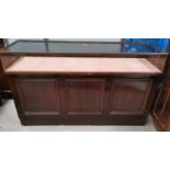 An early/mid 20th century shop display counter with glazed upper section and open shelves under,