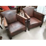 A pair of 1920's oak armchairs, with low seats and leather effect studded upholstery