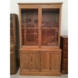 A Victorian pitch pine full height bookcase with 2 glazed door over double cupboard, on plinth base