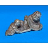 A Meiji period netsuke depicting a man with scroll and child, length 6cm