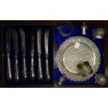 A cased set of silver handle tea knives; an extensively chased Indian white metal dish; 2 pepper