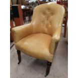A Victorian tub shaped armchair in mustard buttoned leather, on turned legs and castors