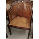 An early 20th century mahogany tub shaped armchair with woven cane seat and back