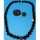 A Whitby jet necklace of faceted beads, a brooch decorated with flowers and a cameo brooch