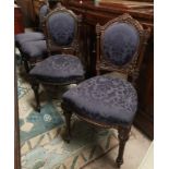 A set of 4 Victorian carved walnut chairs with arched tops and purple fabric