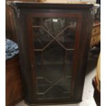 A Georgian oak straight front corner cupboard enclosed by astragal glazed door