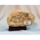 A Chinese jade coloured hardstone carving depicting figures and trees in front of a cave, length 7"