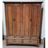 An early 20th century oak Arts & Crafts wardrobe by Arthur W Simpson of Kendal, with lines of carved