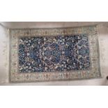 A Persian Kashan hand knotted rug decorated with flora and fauna, on central blue ground, 77" x 47"