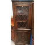 An oak reproduction full height corner display cabinet by Bevan Funnell, with leaded glass upper