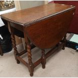 A 1930's oak drop leaf table with oval top, on barley twist legs