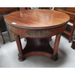 An Empire style mahogany circular coffee table with column legs, shelf below and gilt decoration