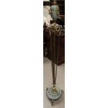A brass standard lamp with vase terminal and swag decoration on trio support on circular 3 footed