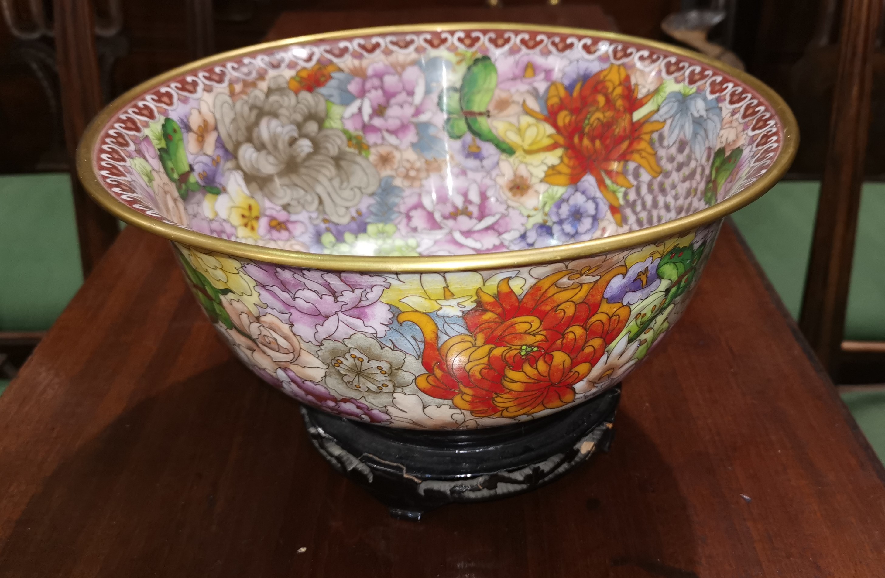 A large modern cloisonne bowl decorated in polychrome with chrysanthemums etc on an ebonised base of