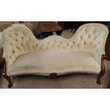 A Victorian walnut framed double spoon back settee on knurled feet, in buttoned cream fabric