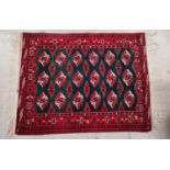 A middle eastern hand knotted rug of Bokhara design with central green ground, 53" x 40"