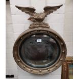An Edwardian convex wall mirror in gilt eagle and ball frame; a barometer in gilt case; a brass