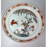 A Chinese Kangxi shallow dish decorated with prancing horse, flowers and trees, in burnt orange,