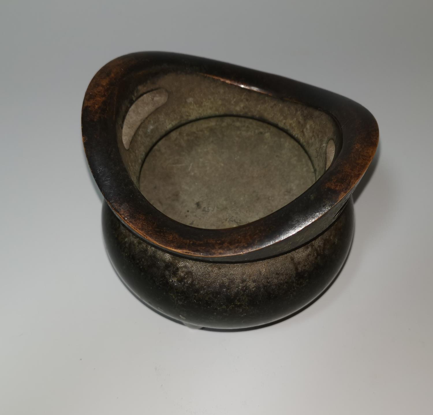 A Chinese patinated bronze incense burner of squat tripod form, flattened loop handles, 12 cm - Image 3 of 3