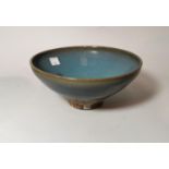 A Chinese high fired glazed bowl in the Sung manner with light blue colouring and patches of violet,