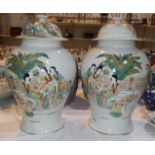 A pair of Chinese baluster shaped lidded vases with mirrored figural scenes to each, (one lid a.f.),