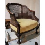 An early 20th century pair of mahogany bergère armchairs, tub shaped, with overstuffed seats in