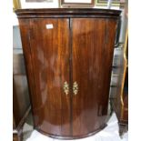 A Georgian mahogany bow front corner cupboard with 3 shelves enclosed by 2 doors, height 94 cm