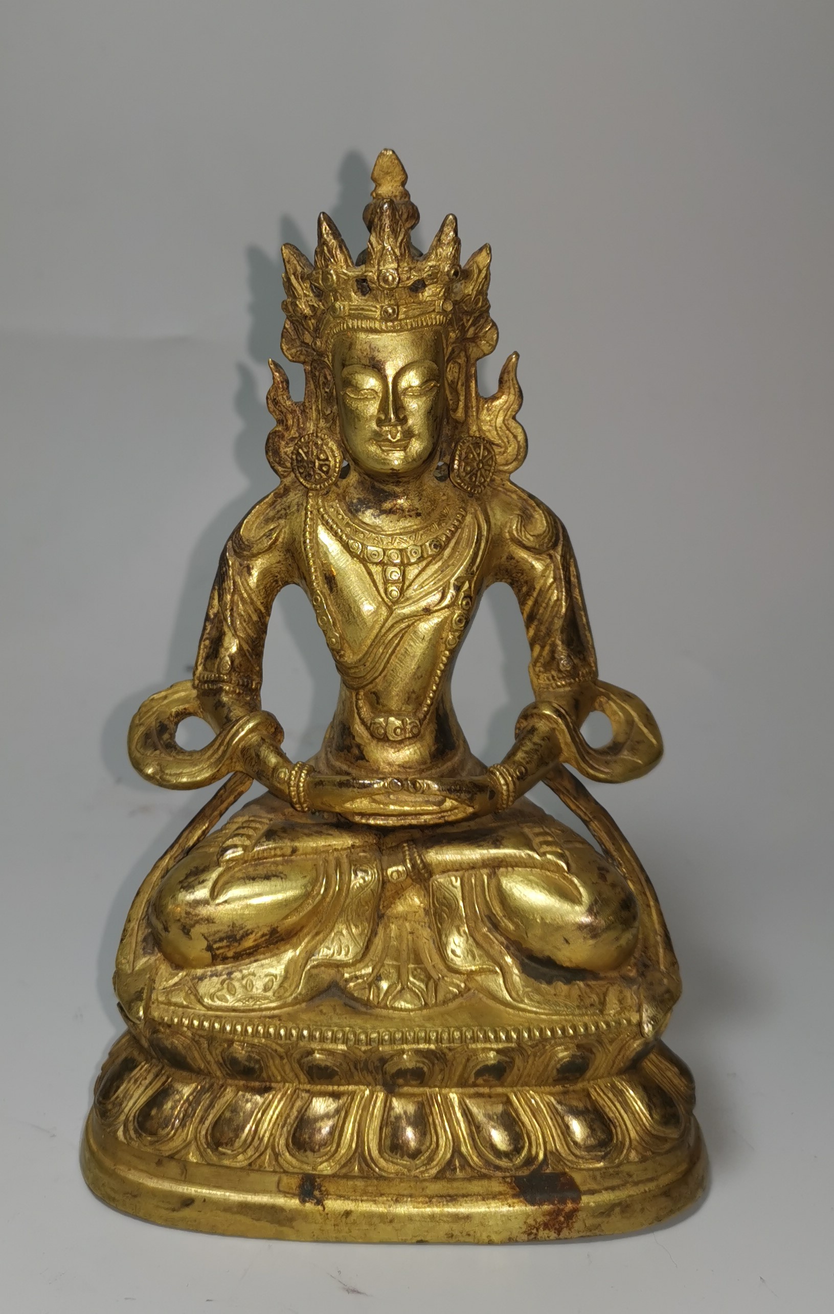 A late 18th / early 19th century Chinese gilt bronze figure of Buddha in the lotus position,