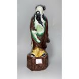 A Chinese porcelain brown/green glazed figure of a man with lotus leaf fan, height 22 cm