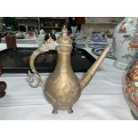 An Indian brass ewer of traditional pear shape with scrolled handle and tapering hexagonal spout, 20