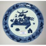 A Chinese plate decorated in blue & white with antiquities on a low table, fish motifs to the rim,