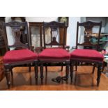 An Edwardian set of 6 mahogany dining chairs with carved pierced splats, overstuffed seats in red