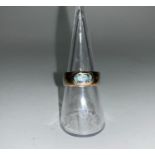 A wide yellow metal ring stamped '9ct' inset with oval aquamarine, 5.4gm