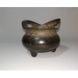 A Chinese patinated bronze incense burner of squat tripod form, flattened loop handles, 12 cm