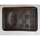 A Chinese carved hardwood ink palette with raised seal characters and oval reservoir, 20 x 14 cm