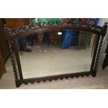 A late 19th/early 20th century bevelled edge mirror in carved oak overmantel frame, arch top and